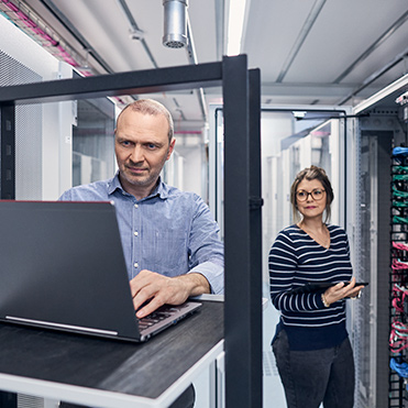 Mann und Frau mit Laptop in Server Raum