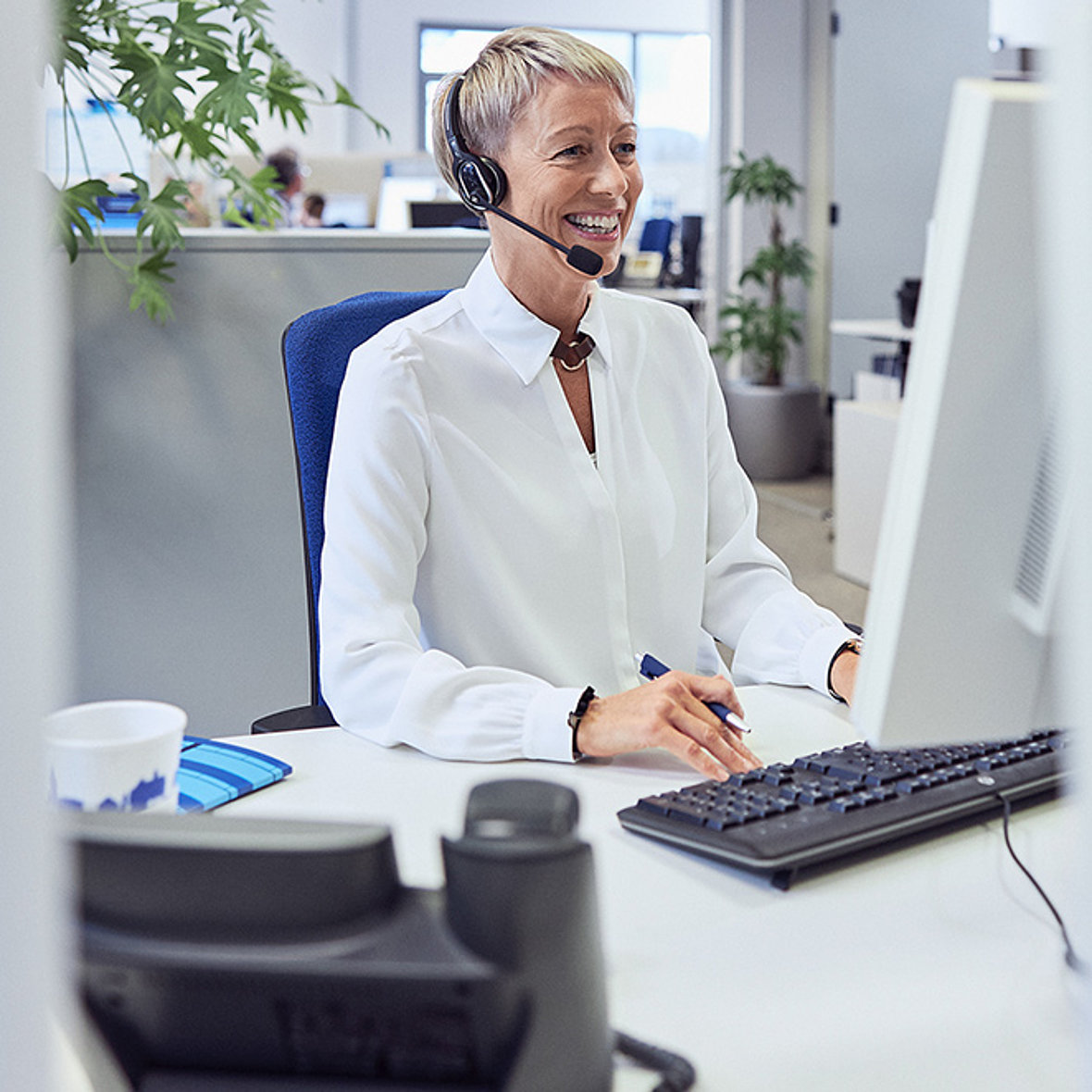 Telefonierende Frau mit Headset an Computer