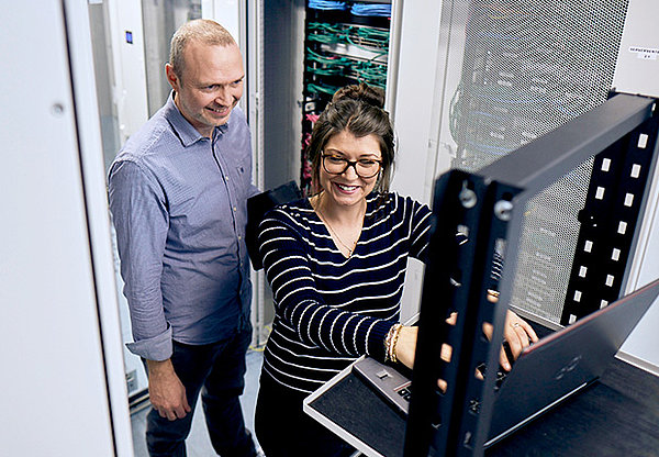 Frau und Mann schauen zusammen auf einen Laptop in einem Server Raum