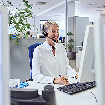 Telefonierende Frau mit Headset an Computer
