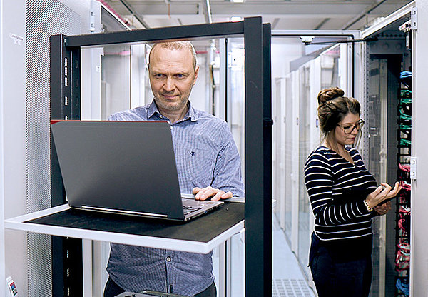 Mann mit Laptop und Frau mit Tablet in einem Server Raum