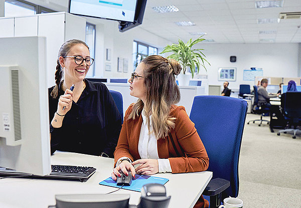 Zwei Frauen am Computer, die sich angeregt unterhalten