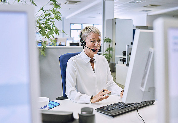 Frau mit Headset telefonierend am Computer