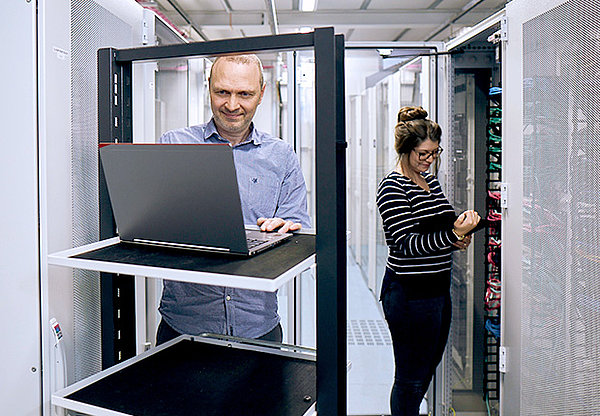 Mann mit Laptop und Frau mit Tablet in einem Server Raum
